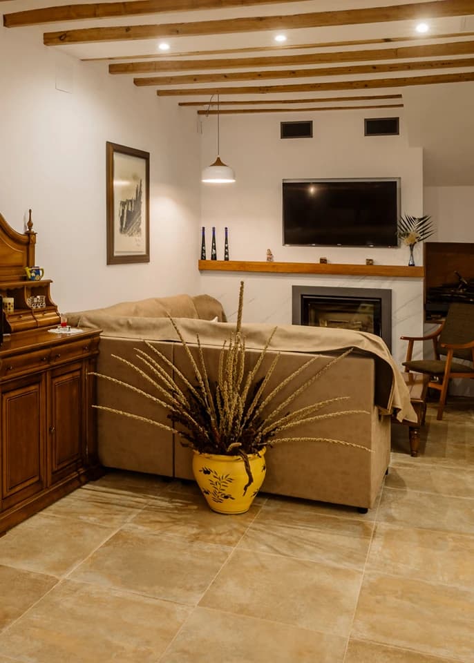 Salón de Ca Iaia Rosario con vigas de madera, sofá y chimenea