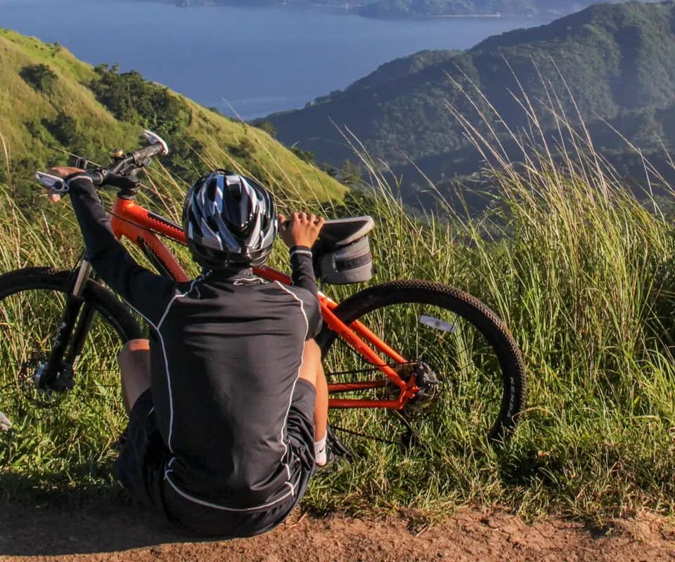 Ciclista descansando frente a un valle de montaña